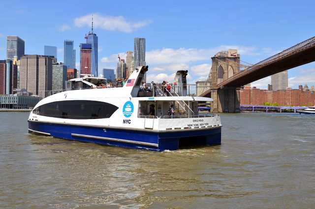 A NYC ferry in front of the New York City skyline.